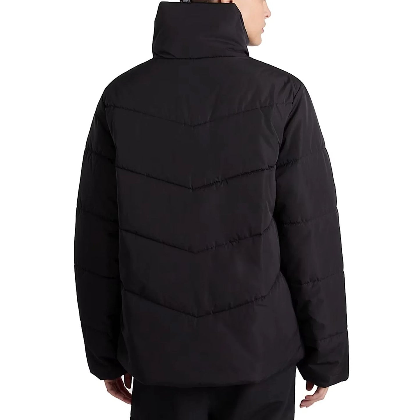 Woman wearing black Vans polyester long-sleeve puffer jacket with zipper and visible logo, back view