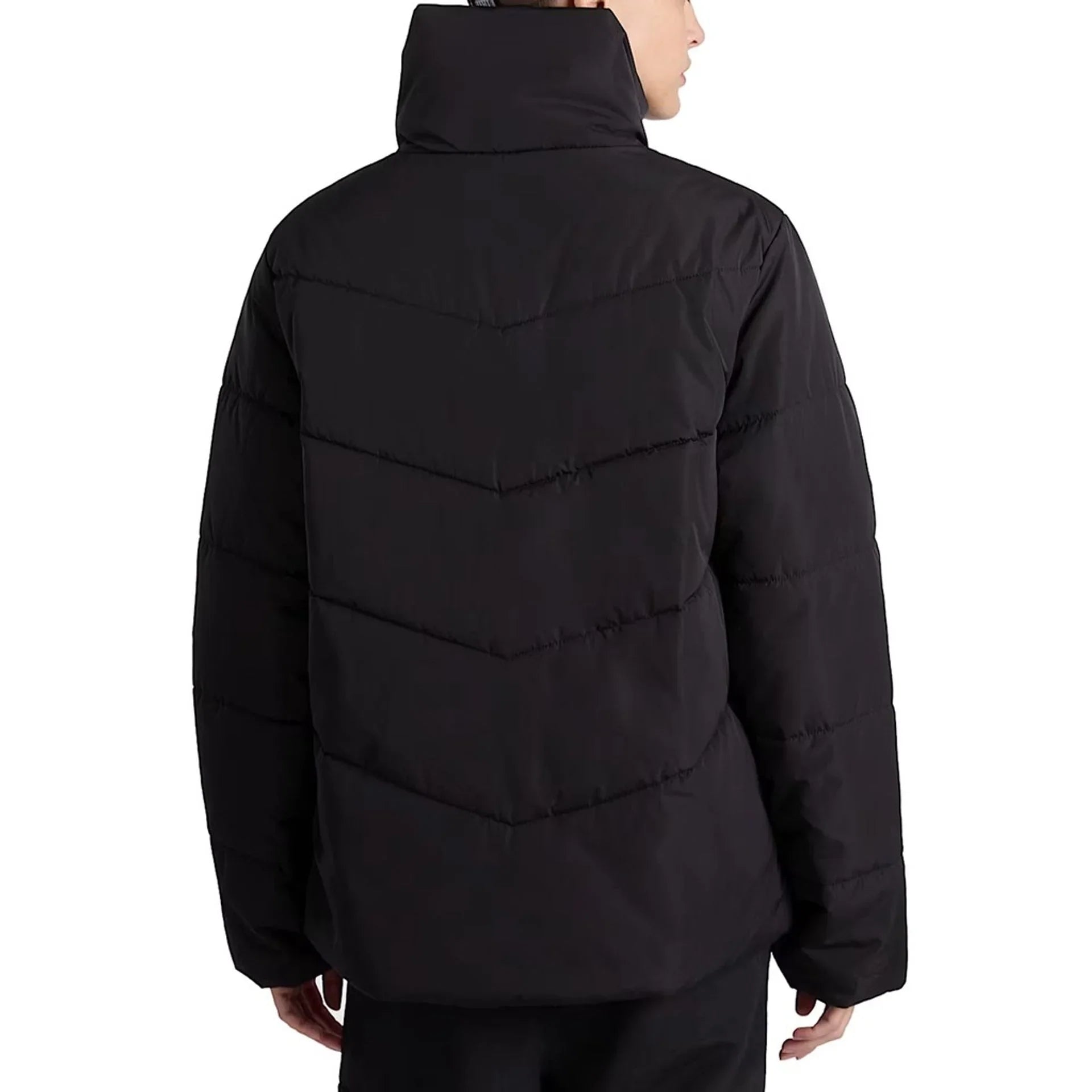 Woman wearing black Vans polyester long-sleeve puffer jacket with zipper and visible logo, back view
