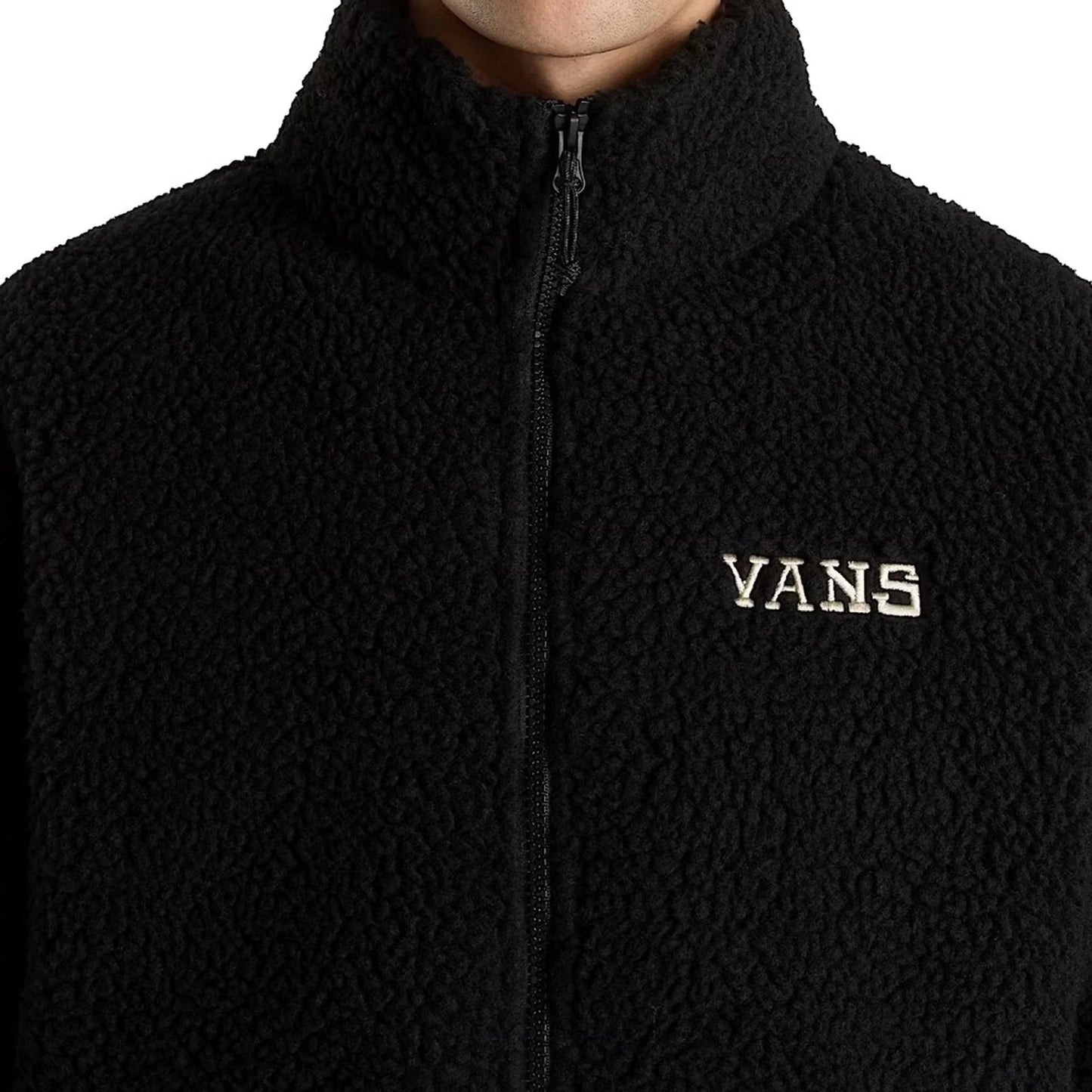 Close-up of a black Vans men's jacket with full zipper and visible Vans logo on textured polyester fabric
